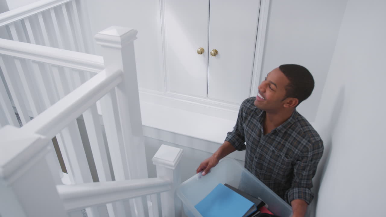estudiante universitario que lleva una caja por las escaleras moviéndose a su alojamiento