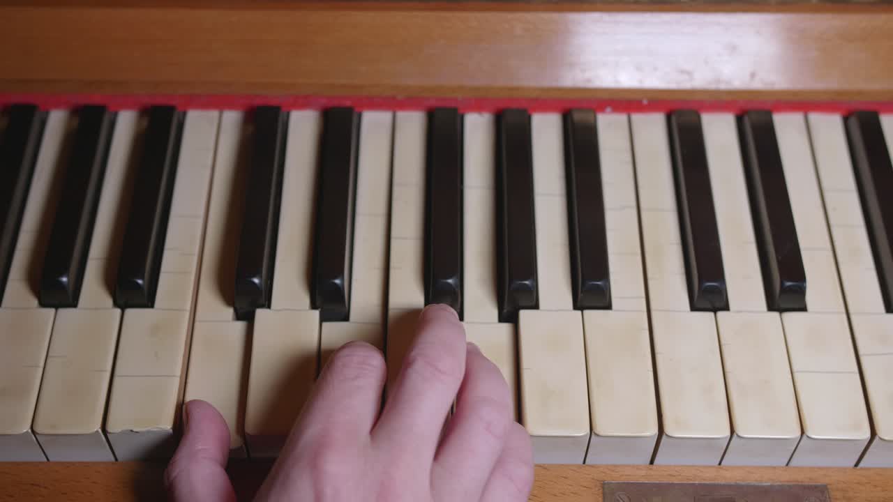 una mano tocando dos acordes en un piano envejecido