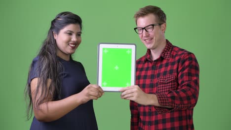 joven pareja de negocios multiétnica juntos contra un fondo verde