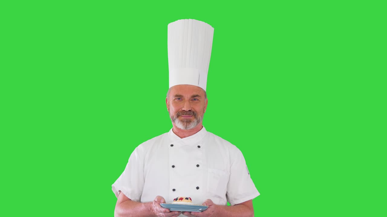 cocinero feliz mirando a la cámara sosteniendo un postre en una pantalla verde, llave de croma