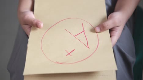 child holding a test paper with a bad grade