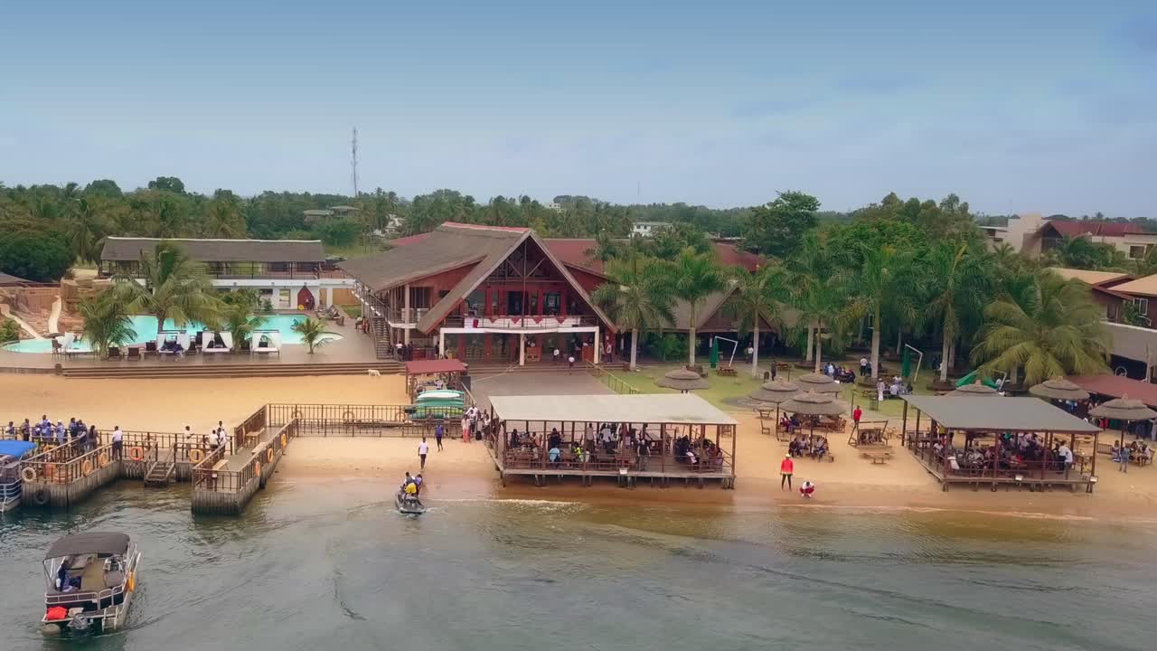 toma cinematográfica de drones inversos de aqua safari resort frente a la playa con botes