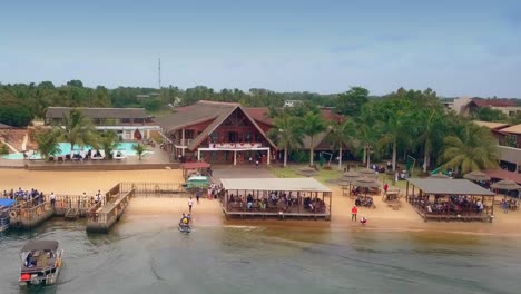 cinematic reverse drone shot of aqua safari resort beach front with boats