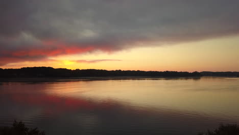 Aerial-view-of-sunrise-over-Reeds-Lake-in-Michigan,-USA