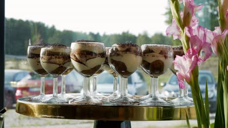 dulce postre de tiramisu en elegantes vasos colocados entre flores