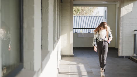 young girl walking in school hallway, adjusting backpack, focused on task, copy space