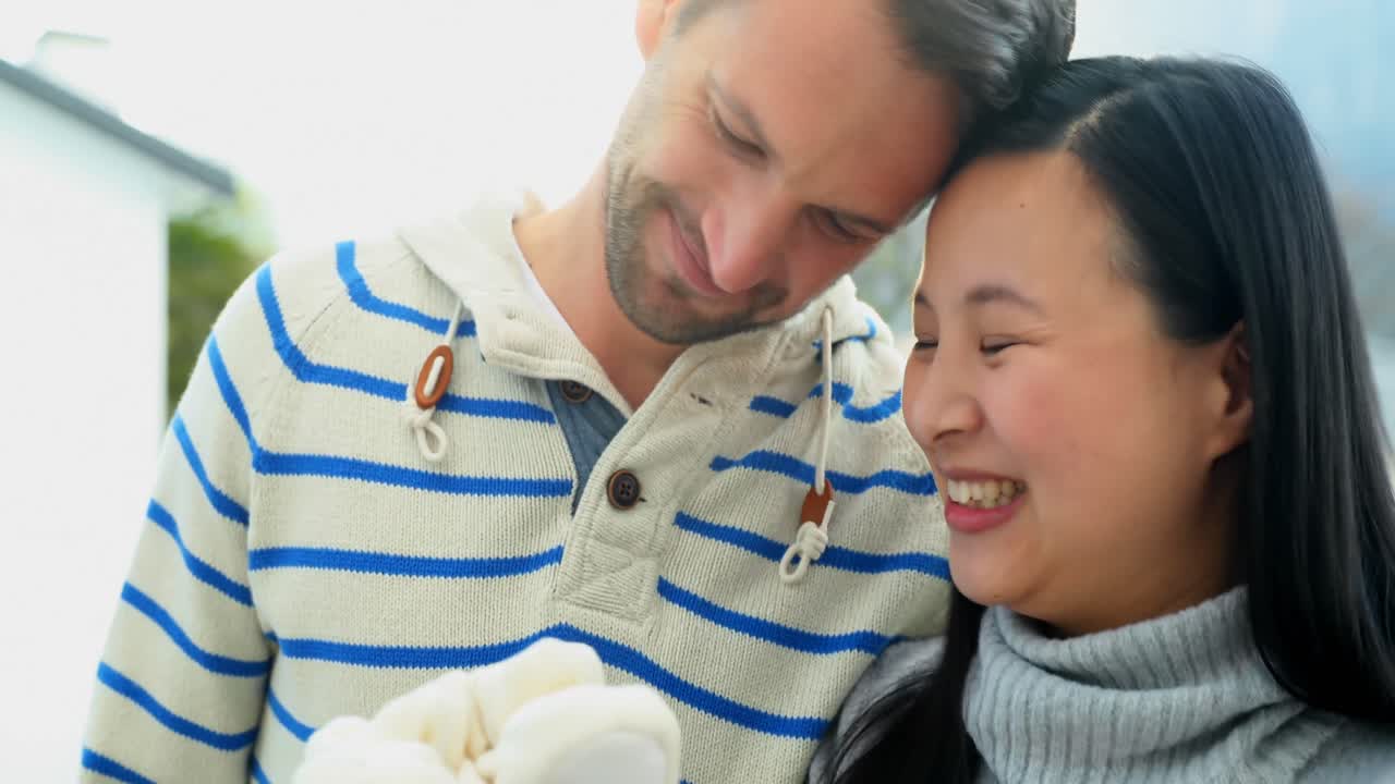 임산부 부부가 테라스 4k에서 부드러운 장난감을 들고 있습니다.