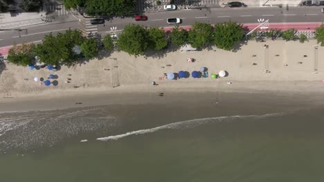 Overhead-View-Of-Sunshade-Umbrellas-On-A-Bustling-Boulevard-Of-BalneÃ¡rio-CamboriÃº-In-Santa-Catarina,-Southern-Brazil