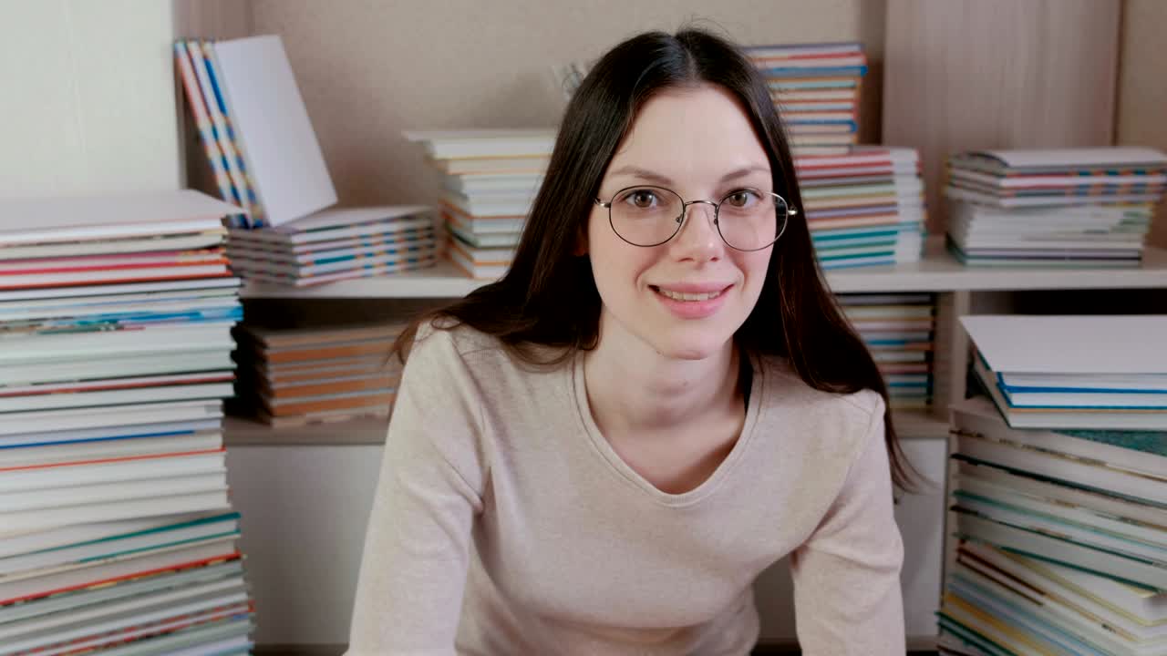 Young brunette woman in glasses is thinking and smiling.