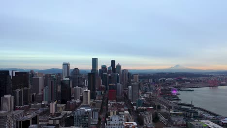 wide aerial of seattle's downtown skyscrapers with mount rainier in the background at dusk