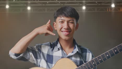 기타를 연주하는 아시아 십대의 클로즈업은 무대에서 제스처와 웃음을 보여줍니다.