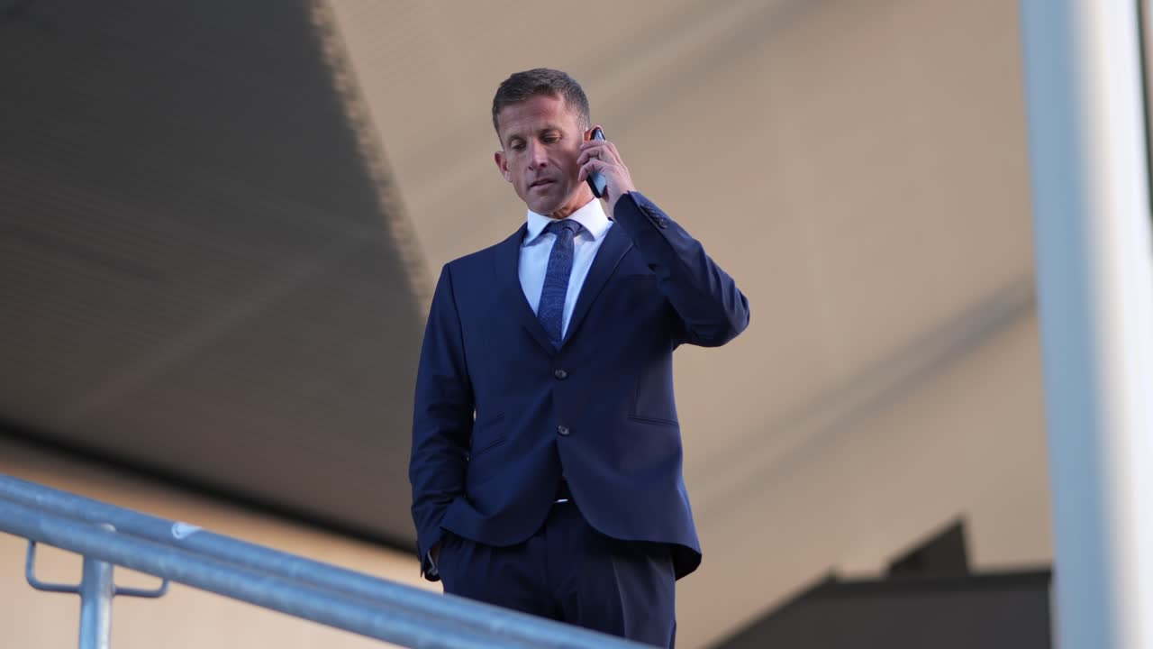 hombre de negocios caucásico haciendo una llamada telefónica al aire libre bajo el techo de un edificio moderno