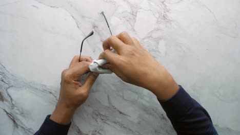 cleaning eyeglass with tissue close up