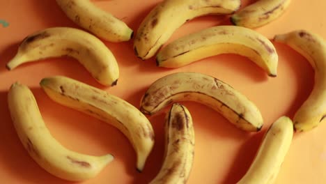 plátanos húmedos deliciosos maduros giran en el sentido de las agujas del reloj sobre un plato negro sobre un fondo amarillo