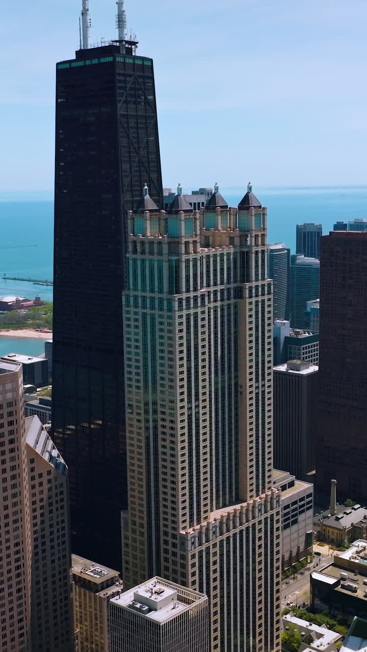 Beautiful skyscrapers of Chicago standing on the waterfront of Lake Michigan. Aerial view of the buildings at the backdrop of blue water and sky. Vertical video