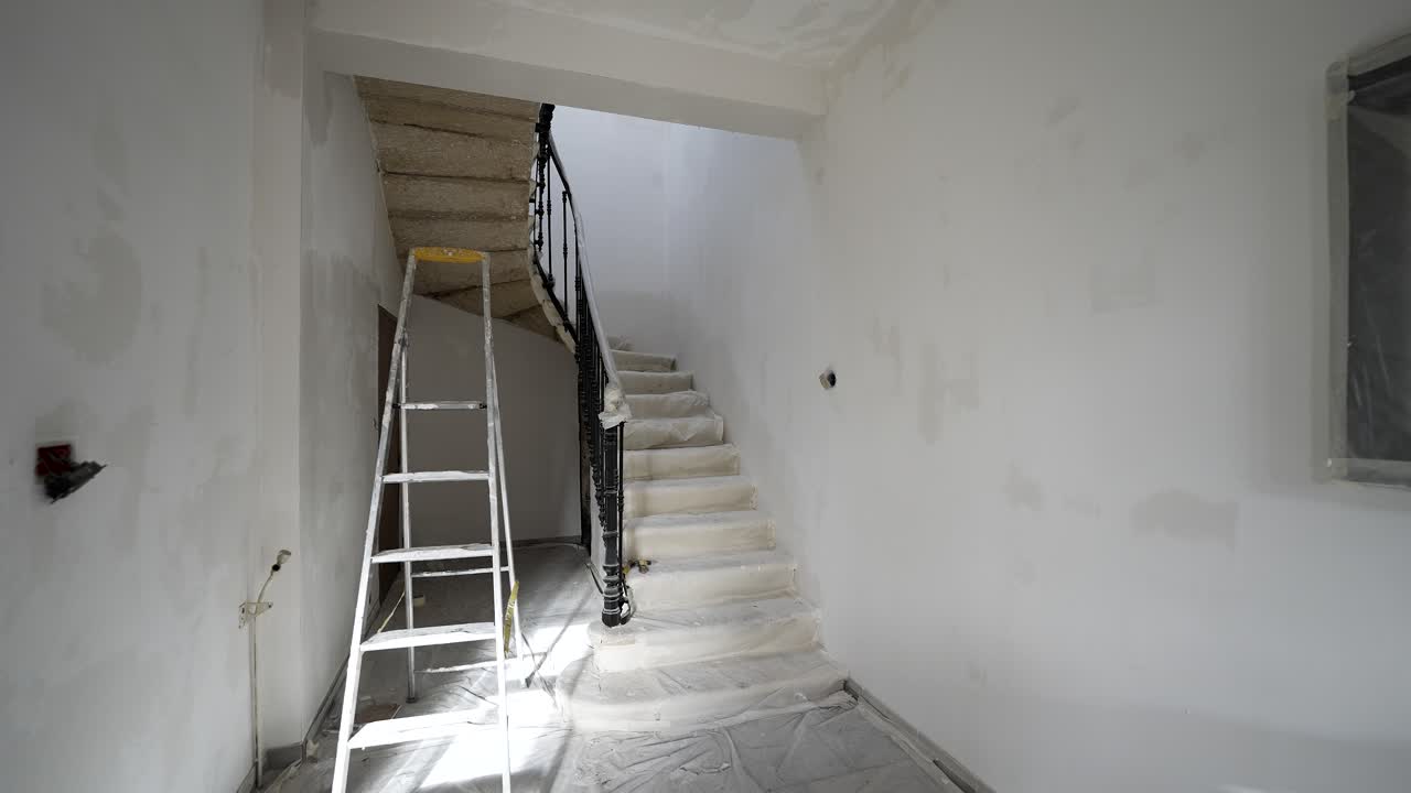 Home spiral staircase draped on painter's cloth for renovating, Stable dolly in shot