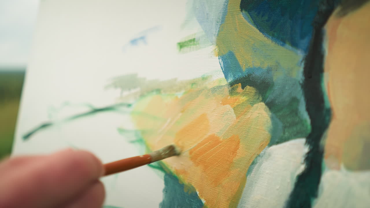 A close-up shot of an artist s hand delicately applying paint to a canvas with a small brush. highlighting the artist's technique and attention to detail