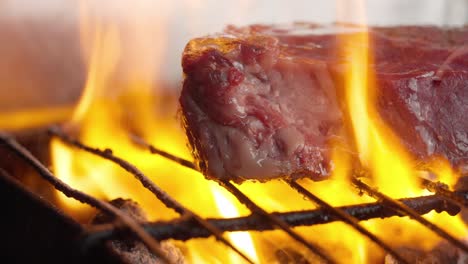 Close-up-of-grilled-fillet-steak-between-flames-and-embers-of-barbecue-charcoal