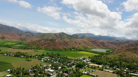 Aerial-view-of-green-wide-field-and-rocky-mountain-with-clear-sky-during-daytime-in-4K-quality