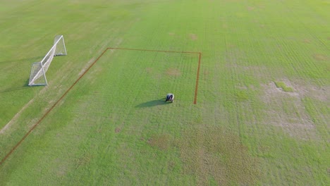 aerial view of a robot autonomously painting precise lines on a soccer field under clear daylight
