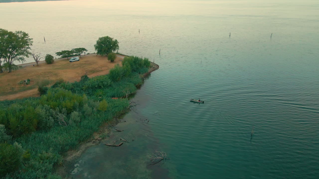 Pescatore in riva al Lago Trasimeno alle prime luci dell'alba in Italia.