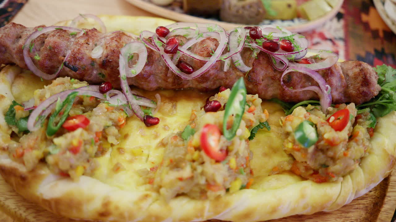 Carne picada a la parrilla servida sobre pan plano con verduras y hierbas