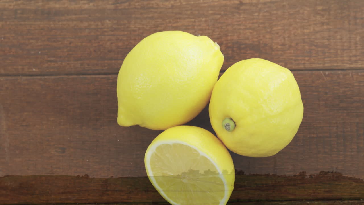 Bright yellow lemons on wooden surface, one cut in half, showing inside