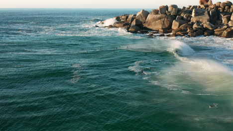 A-group-of-surfers-waiting-on-the-next-wave-while-enjoy-the-sunset-in-Llandudno,-Kaapstad