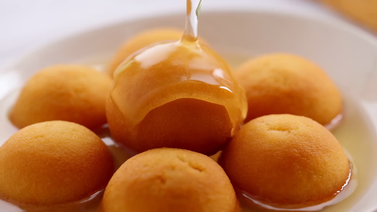 Sciroppo dolce versato su un dessert indiano dorato.