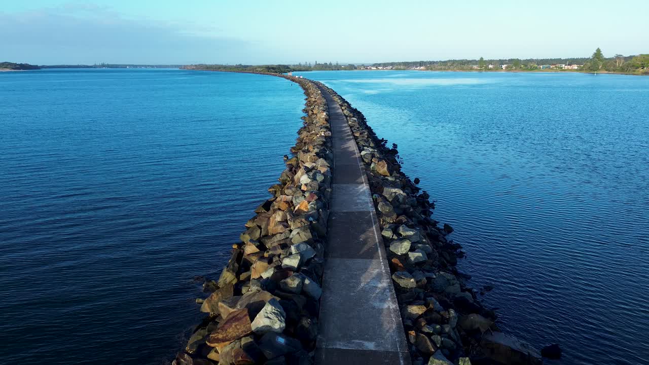 Drone aerial landscape of rocky break wall pathway bridge across the Manning River inlet channel lake lagoon water system in Harrington near Taree Australia travel tourism nature environment outdoors