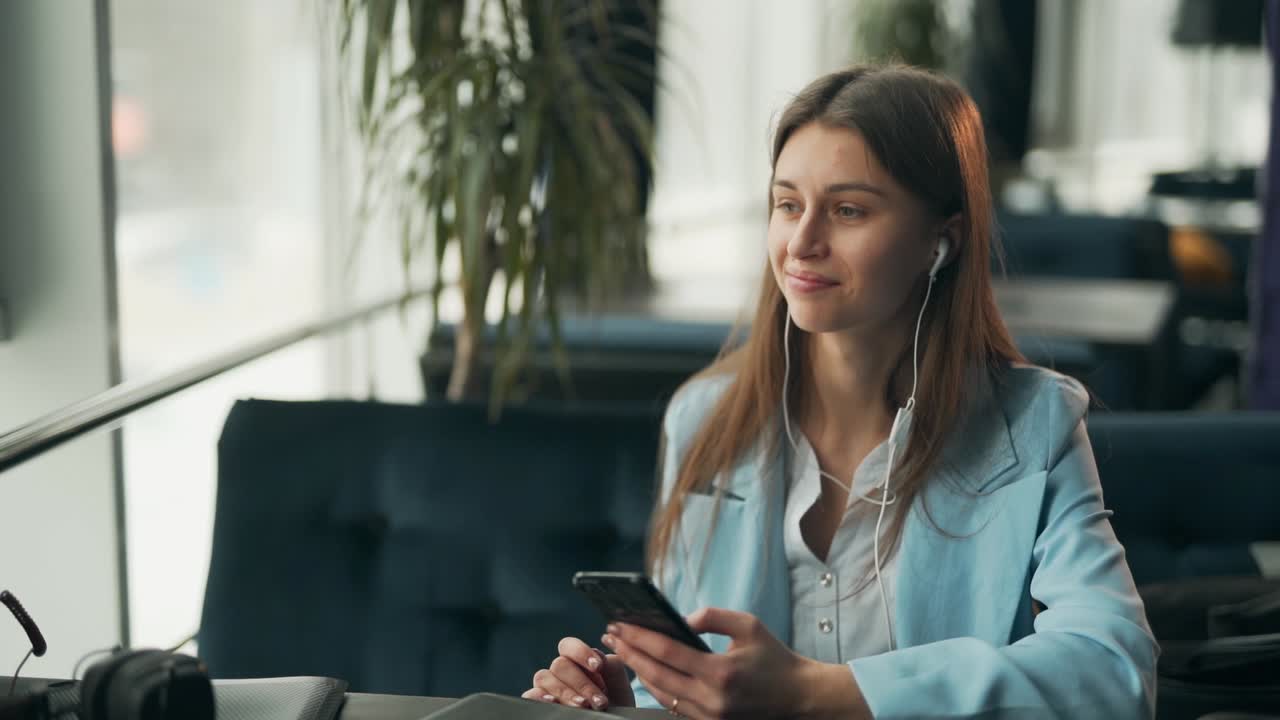 bella chica con traje de negocios escucha música sentada en un café