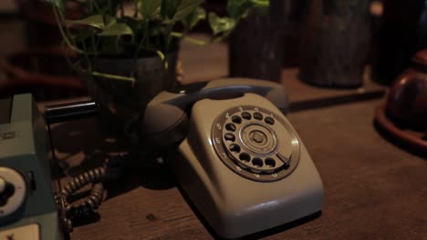 Zoom-out-vintage-telephone-on-wood-table,-slow-motion