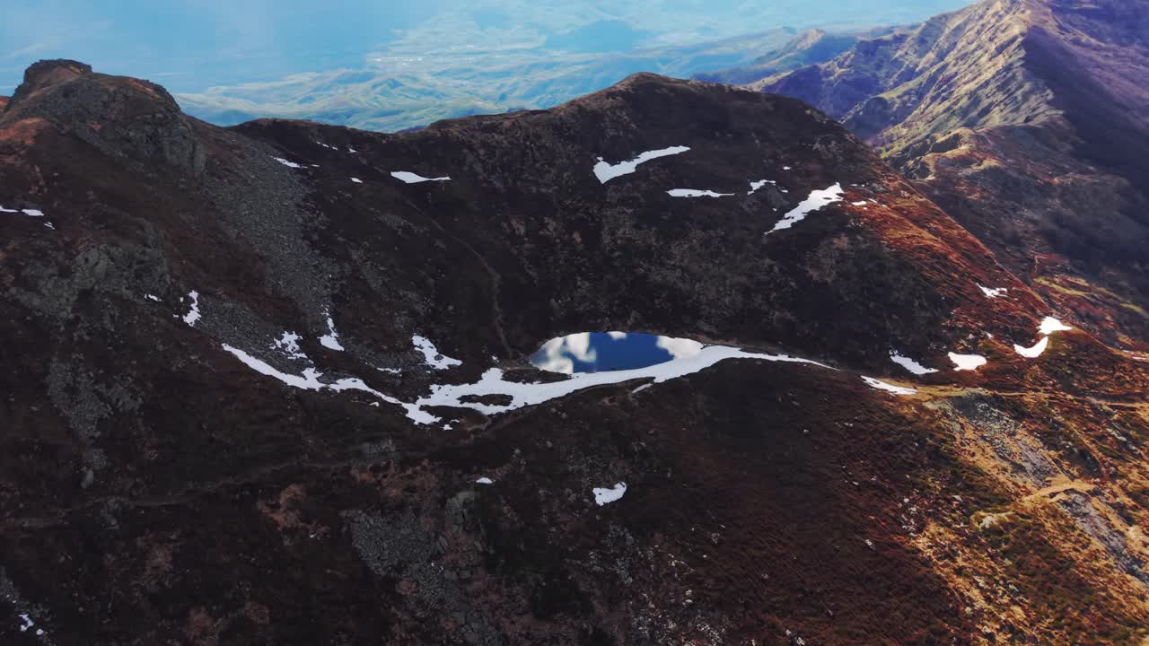 Snowy mountain lake in the Dolomites, scenic aerial with rugged peaks and spring melt