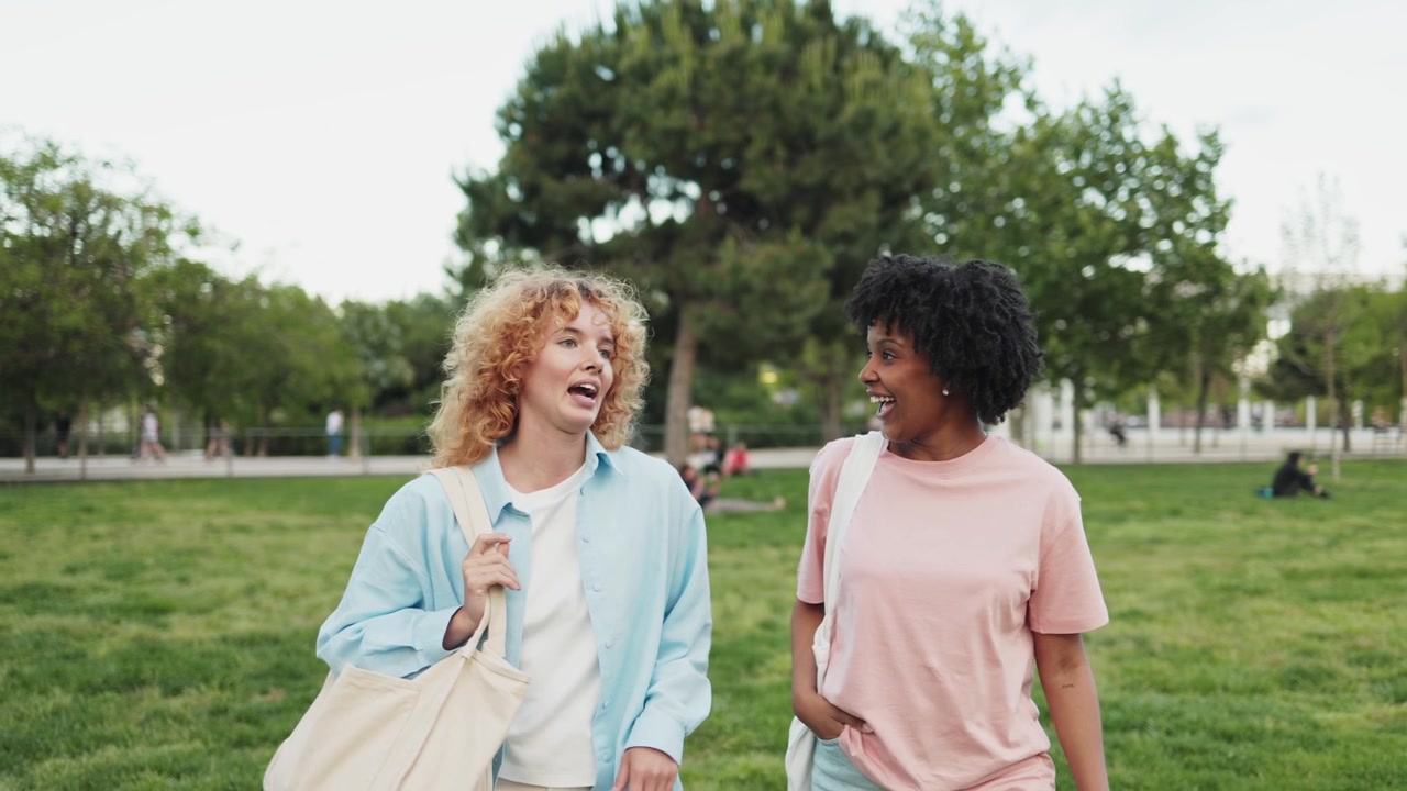 Two Happy Young Women Walking and Talking in a Park