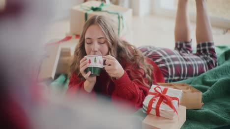 hermosa mujer bebiendo café mientras yacía en el suelo durante la navidad