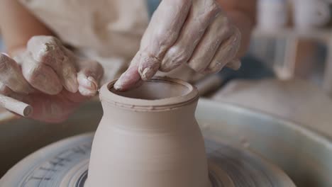 female potter makes a pot on the pottery wheel.