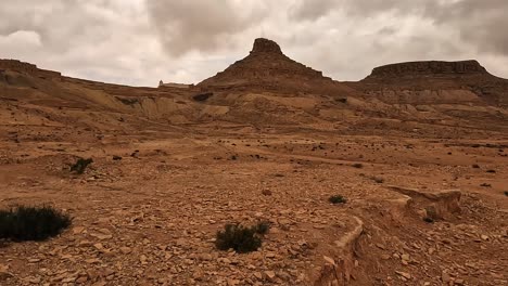 driving along desert road with ksar guermessa troglodyte village in background in tunisia on cloudy day