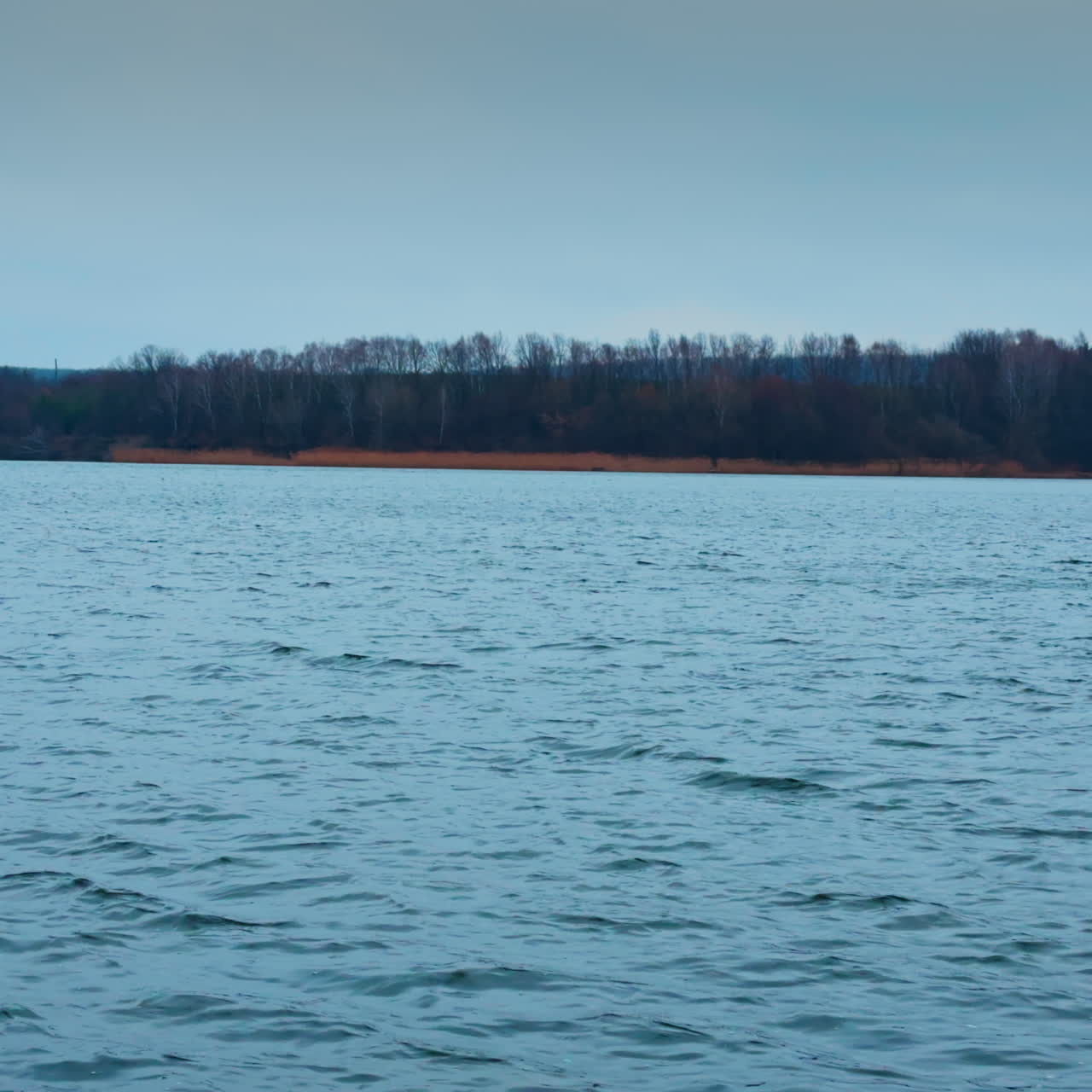 Cold late autumn day on the big river. Grey waterscape reflecting overcast skies above.