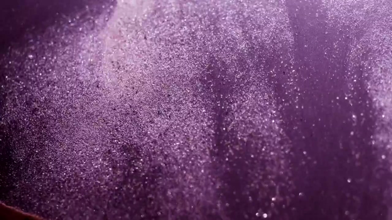 Lilla abstrakte sandpartikler, der strømmer i slowmotion.