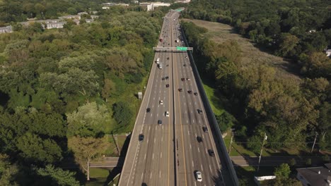 Cinematic-4K-Aerial-Pan-up-of-NYC-highway-lush-greenery-blue-sky