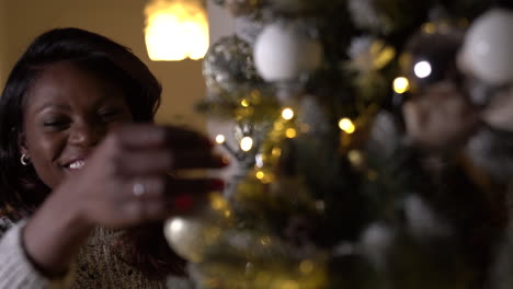 happy, smiling black afro-american woman decorating a christmas tree