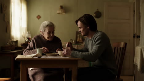 a man feeding an elderly woman at a table