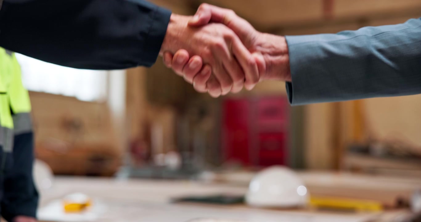 Operai edili che si stringono la mano in officina