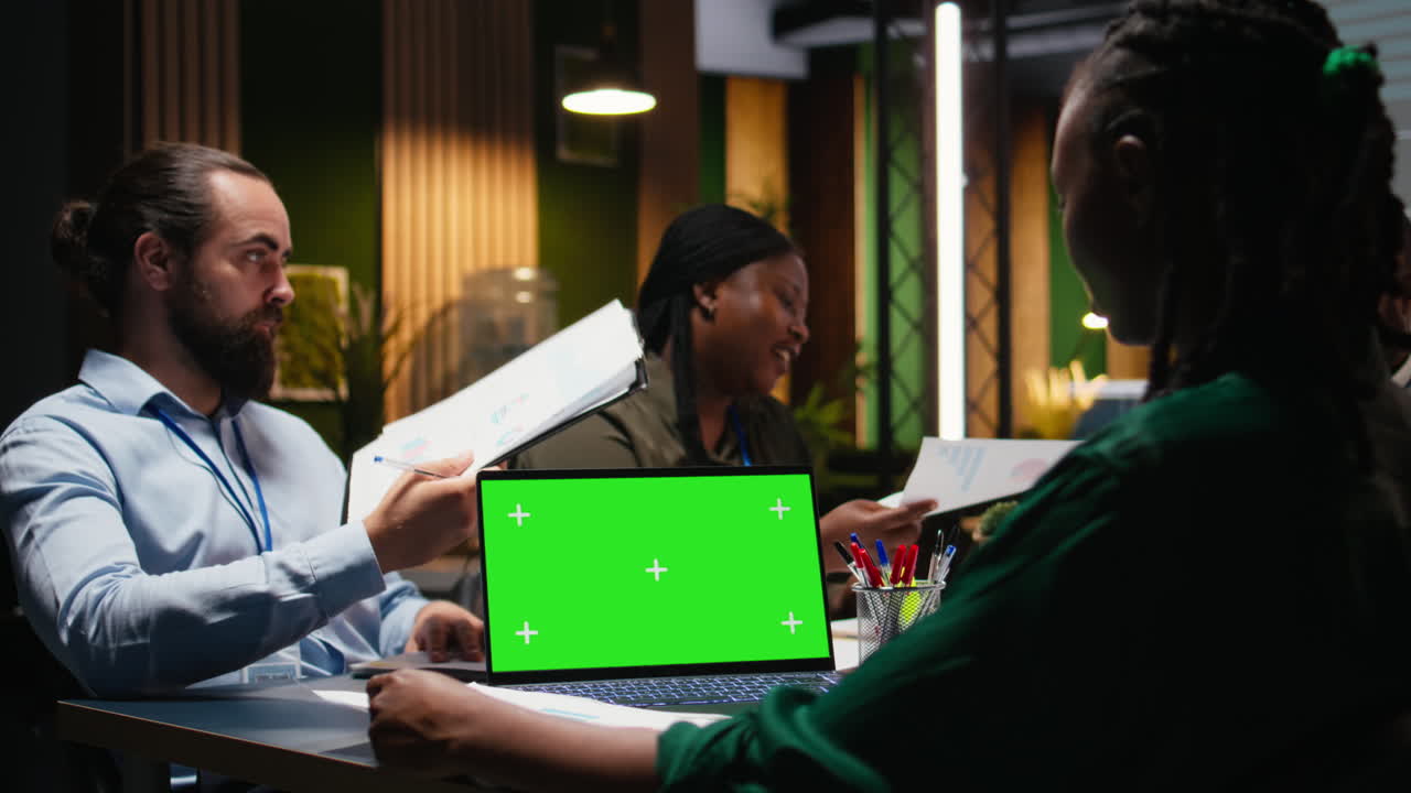 Multiethnic staff working at night in office with chroma key on laptop