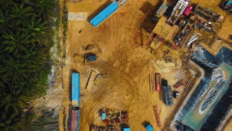 Cinematic-Drone-Footage-of-Onshore-Drilling-Rig-equipment-structure-for-oil-exploration-and-exploitation-in-the-middle-of-jungle-surrounded-by-palm-oil-trees-during-sunset-and-high-oil-price