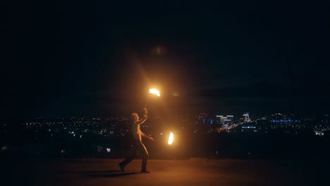 young blond male dances with two burning torches