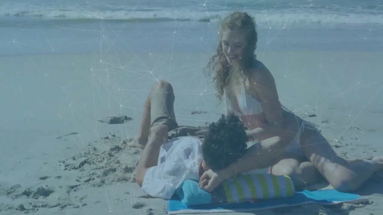 Donna che tocca la spalla per iniziare un massaggio alla schiena su un asciugamano a righe, con una coppia che si rilassa in una spa sulla spiaggia