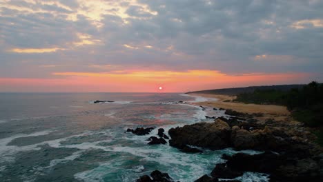 aerea sulla costa rocciosa e vista sulla spiaggia di playa paraiso con maestoso tramonto arancione all'orizzonte