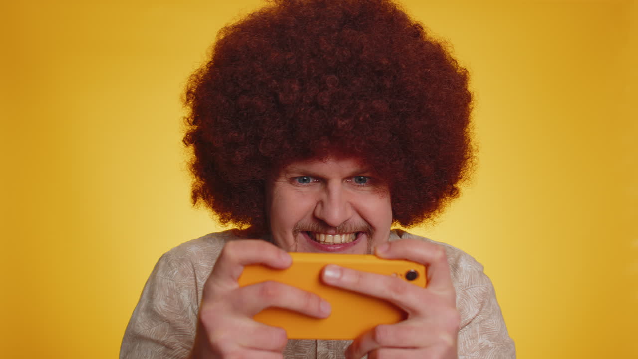 Worried happy winner man playing drive racing or shooter video games on smartphone gadget app