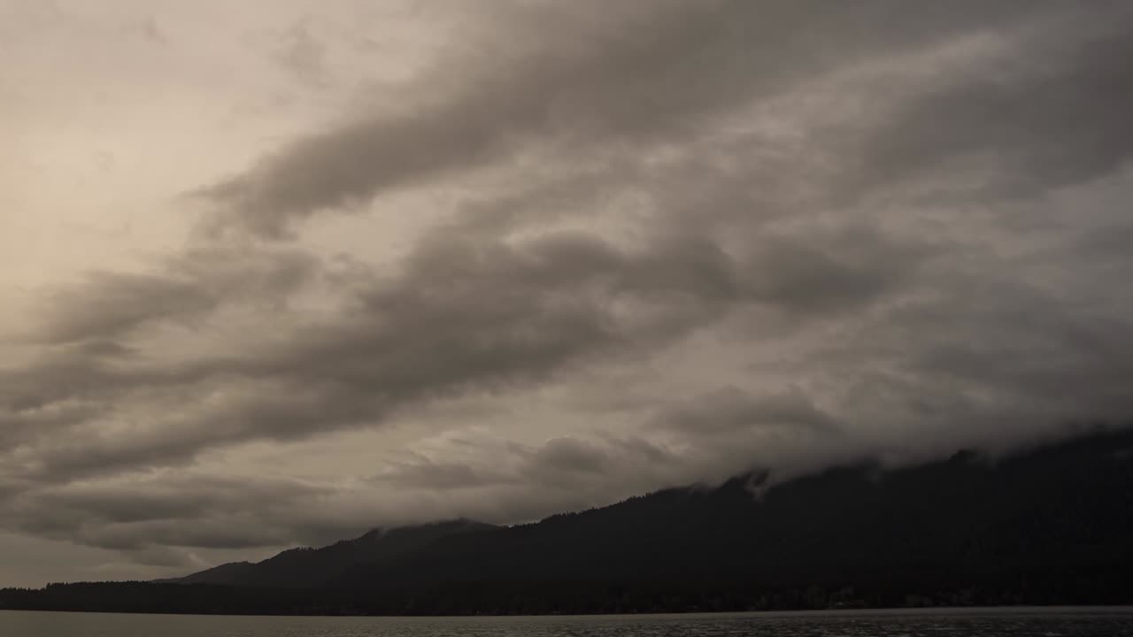 Dramatic gray storm clouds criss cross Lake Quinalt Olympic national Forest, zoom out pan left